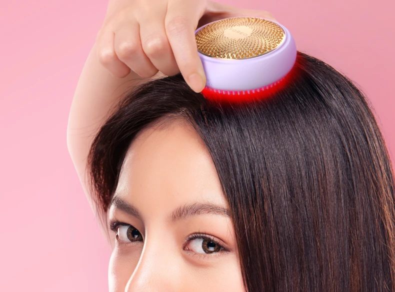 Woman parting her dark hair with a lavender FOREO LUNA 4 hair scalp massager