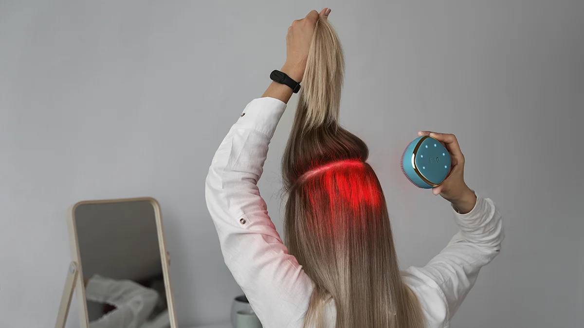 FAQ 301 skin care beauty trends, woman parting her hair to treat the scalp with red LED therapy