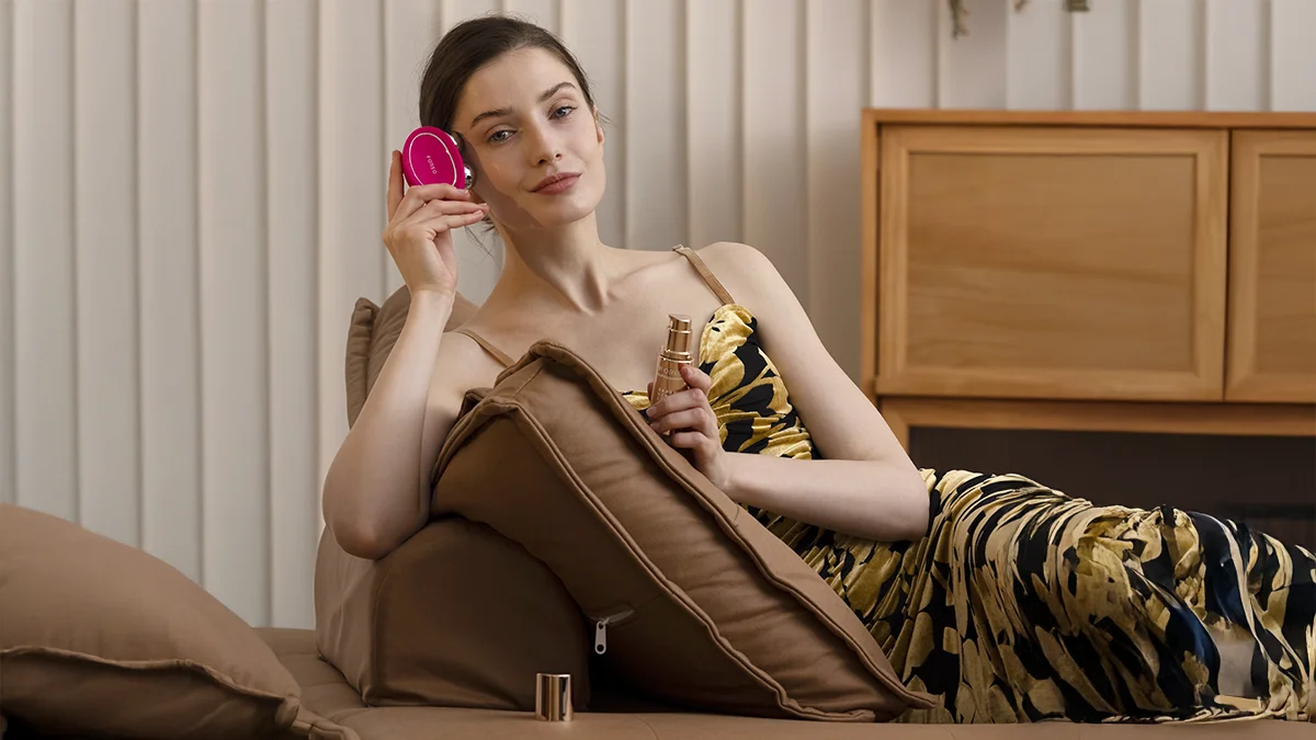 A beautiful woman using FOREO BEAR 2 firming face care routine on a couch