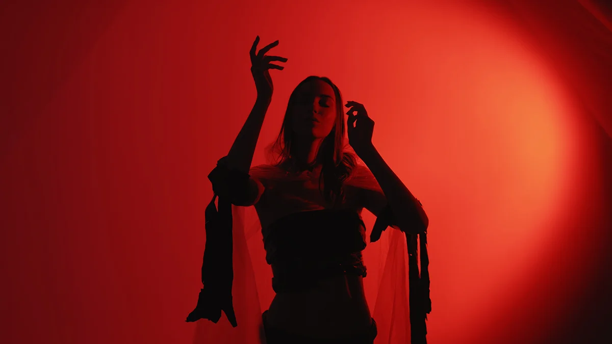 A young woman in flowy clothes dancing in red lights