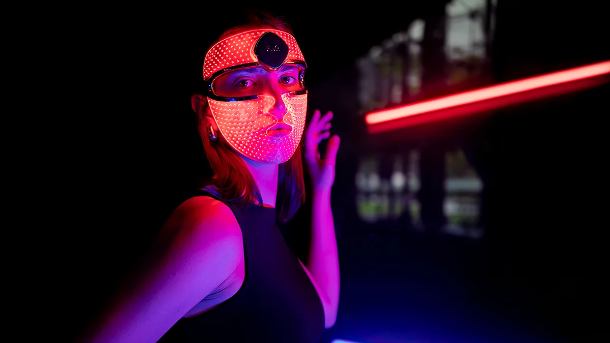 a modern and attractive young woman wearing a red light therapy face mask