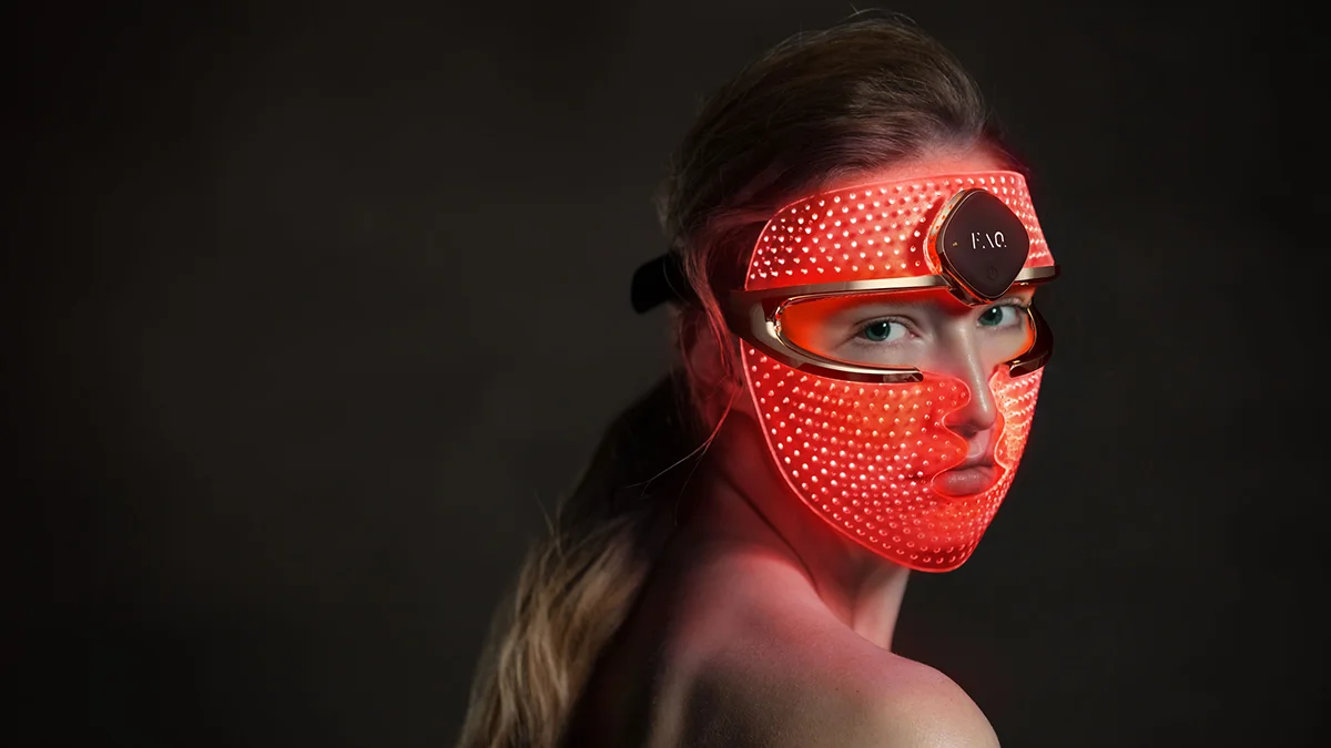 a woman looking over her shoulder wearing FAQ 202 red light face mask