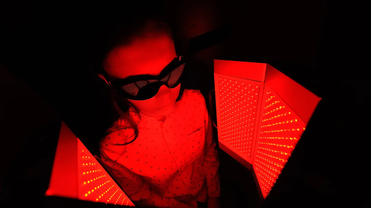 A woman in a dark room recieving red light therapy