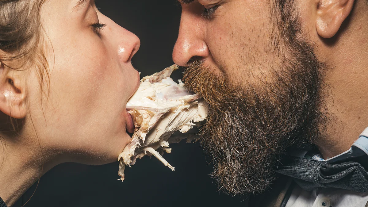 A couple eating a chicken together, lady and the tramp way