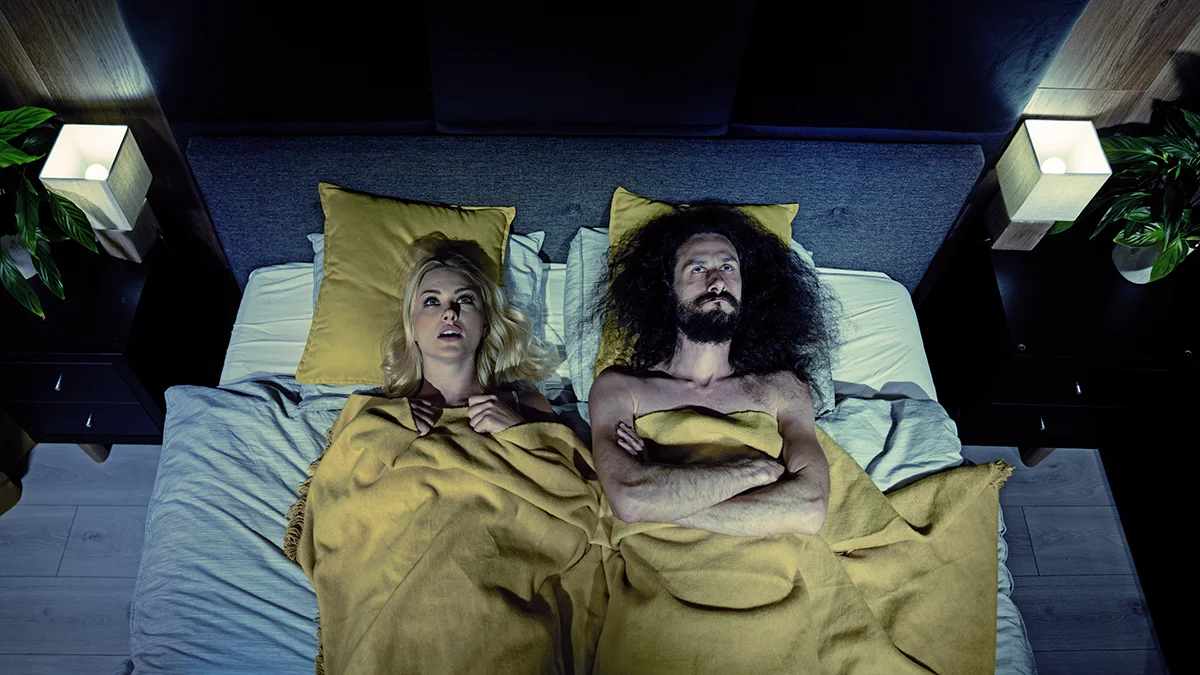 A funky couple lying in bed with yellow pillows wandering how long does the honeymoon phase last