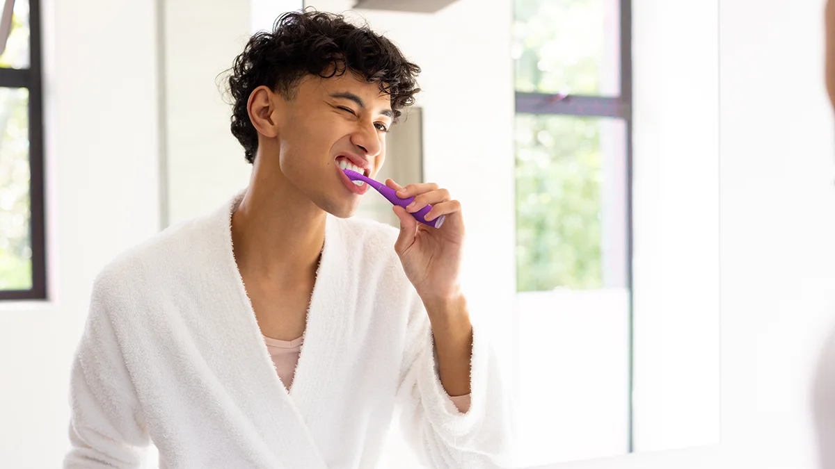 A young man brushing teeth with issa 4 silicone sonic electric toothbrush