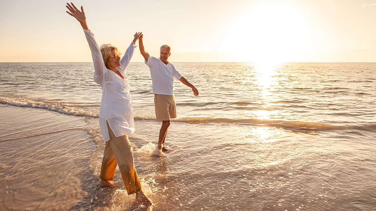 Man and woman walking down the beach at sunset holding hands