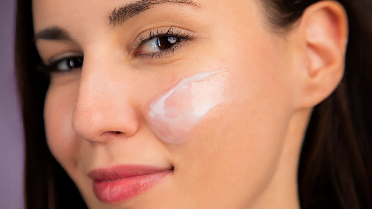 A woman using KIWI mattifying moisturizer