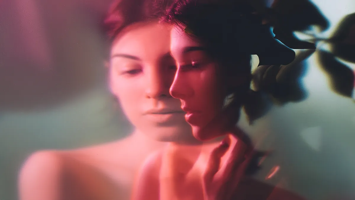 A dreamy portrait with long exposure of womans face shown from teh profile and en face in red light