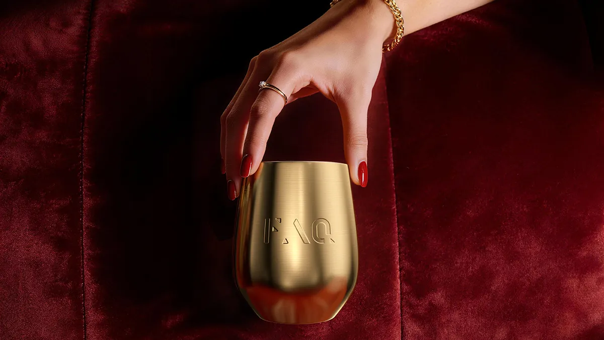 FAQ pure green juice in a gold cup held by woman with red nails