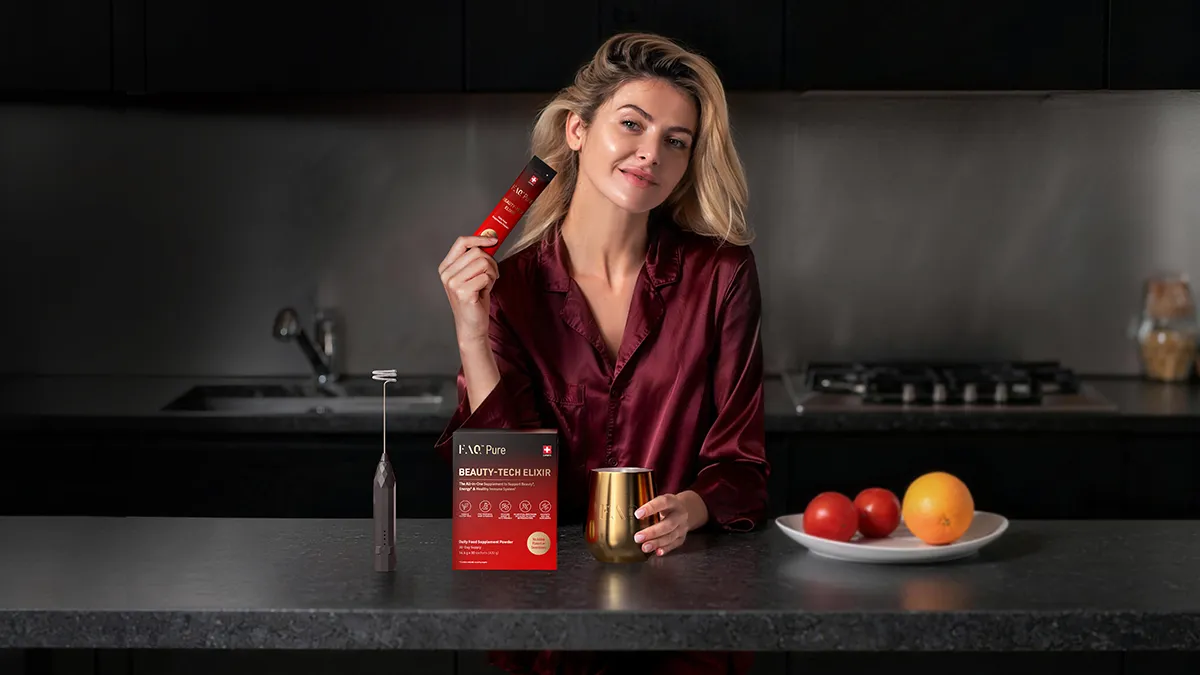 A beautiful woman in a bathrobe making FAQ pure green drink in a modern kitchen