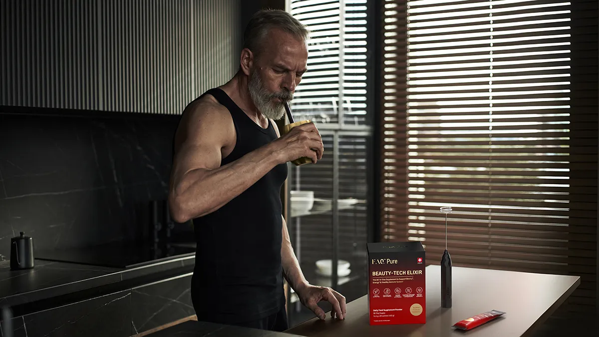 A muscular older man drinking the FAQ supergreens powder