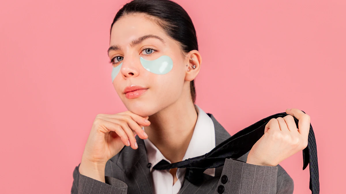 A young woman ina  business suit wearing baby blue IRIS eye patches to depuff