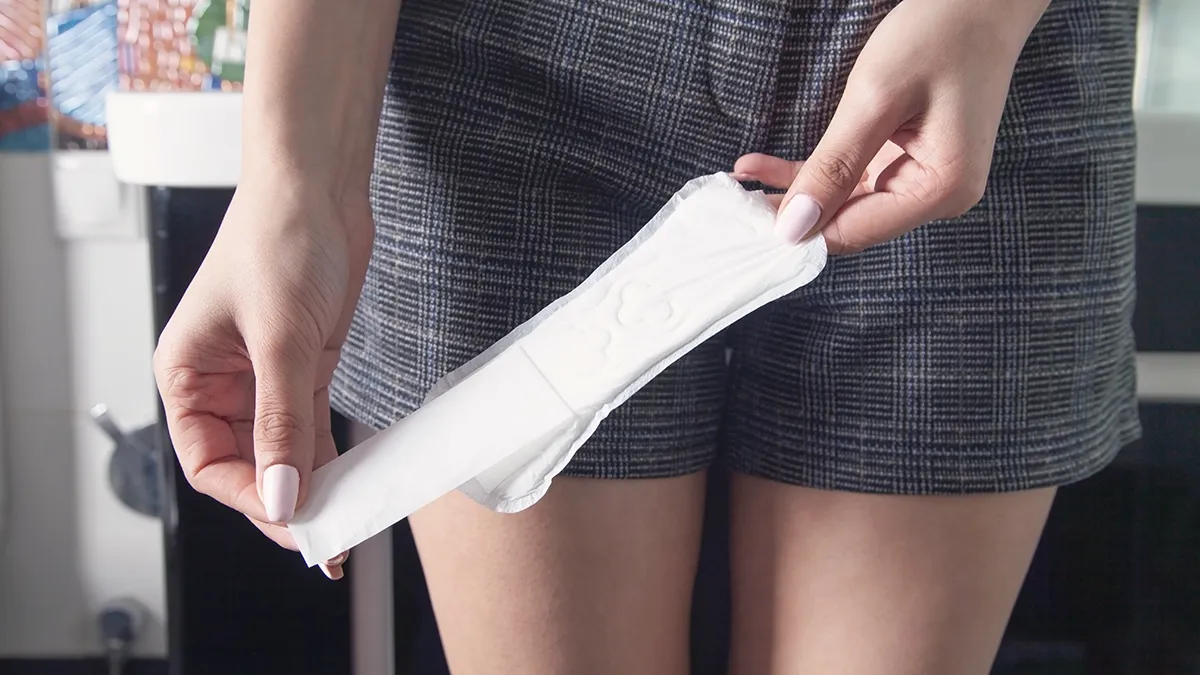 a woman in shorts opening a sanitary pad