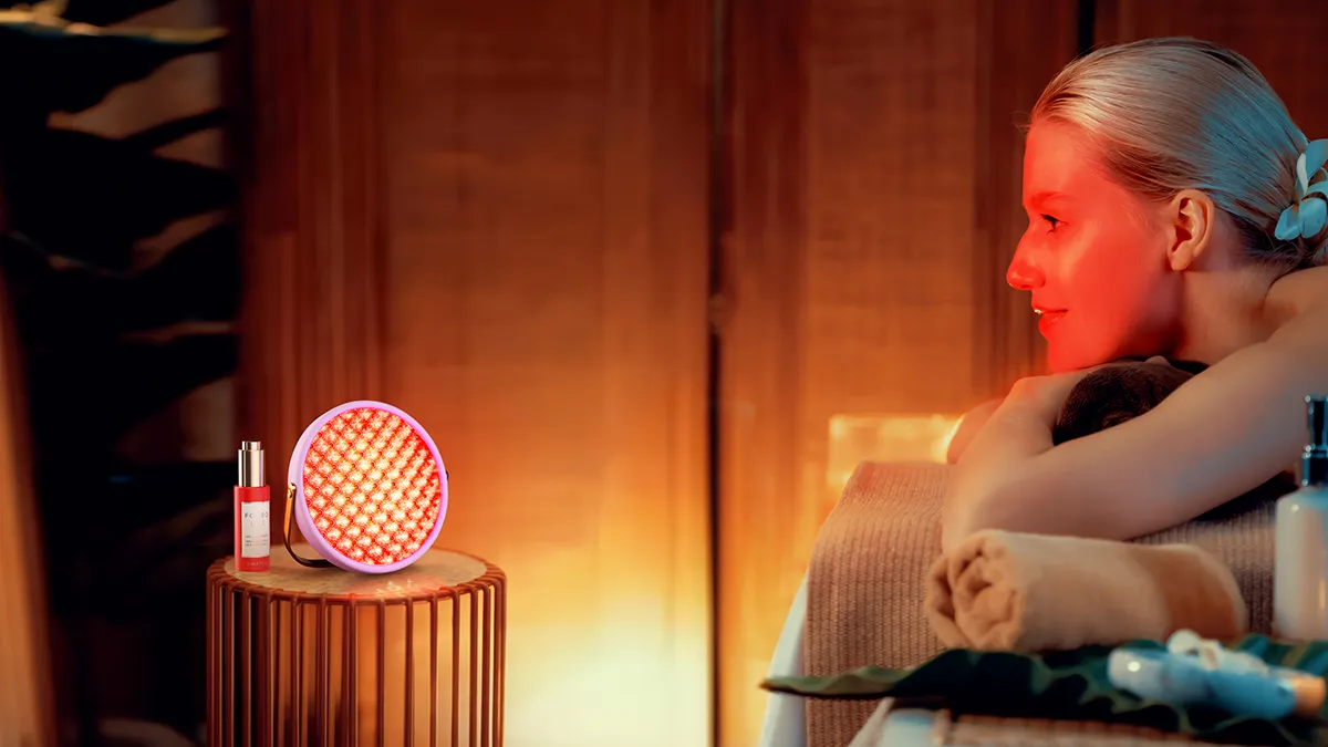 A woman using UFO lighthouse red light therapy panel