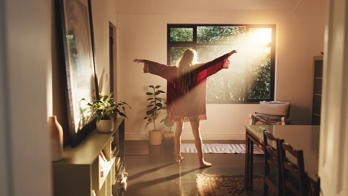 A woman getting some early morning sunlight at the window