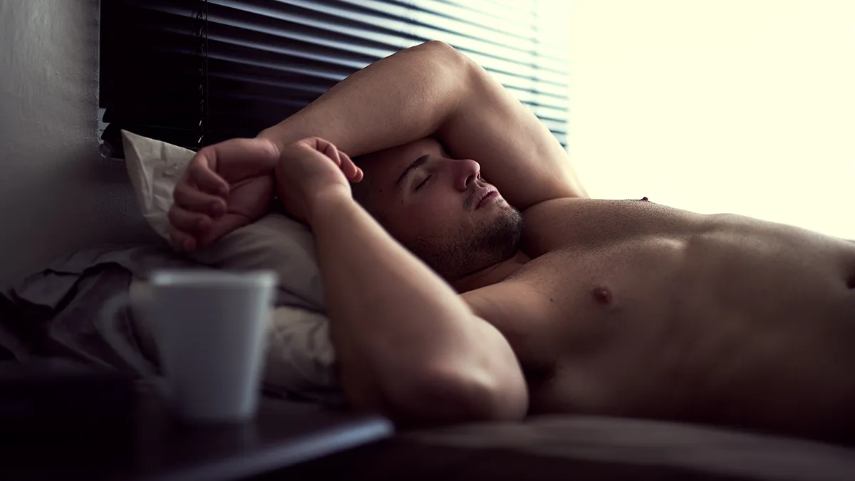 A tired muscular man with a naked torso, lying down exhausted