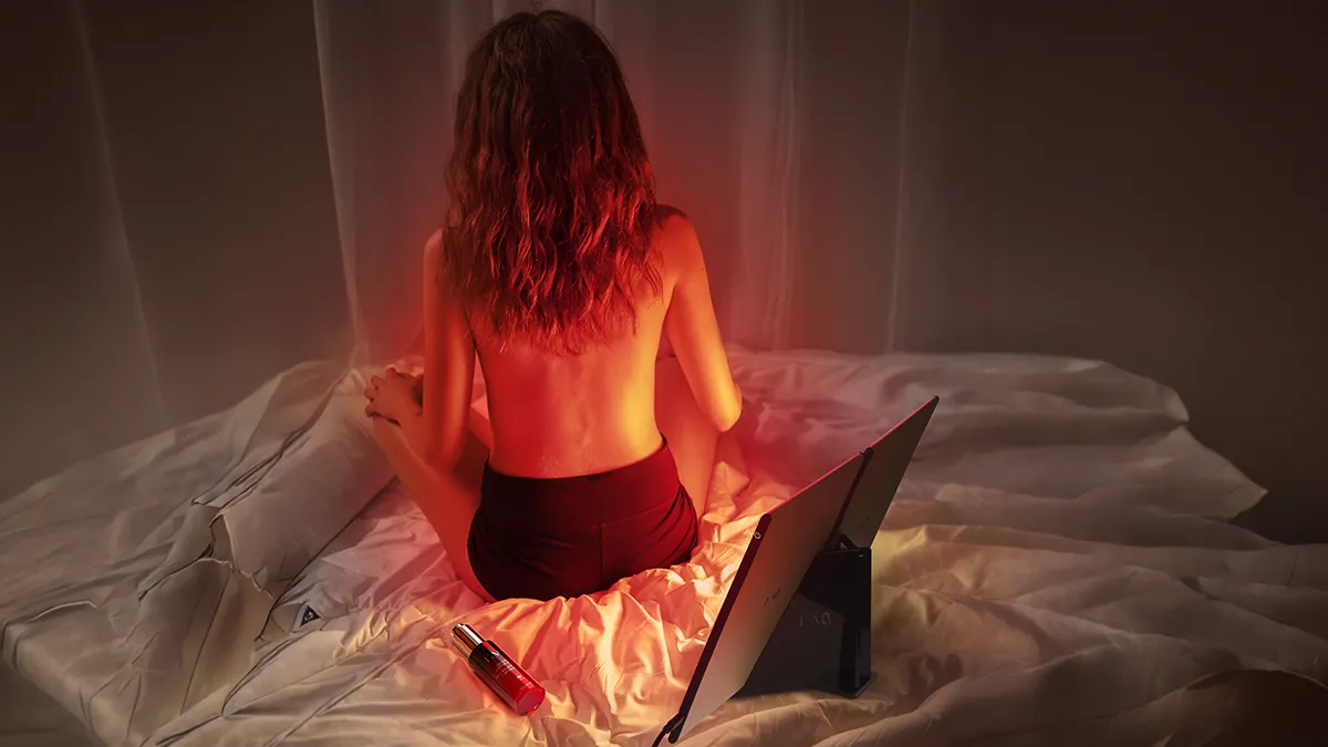 A woman using FAQ dual red light therapy panel at home