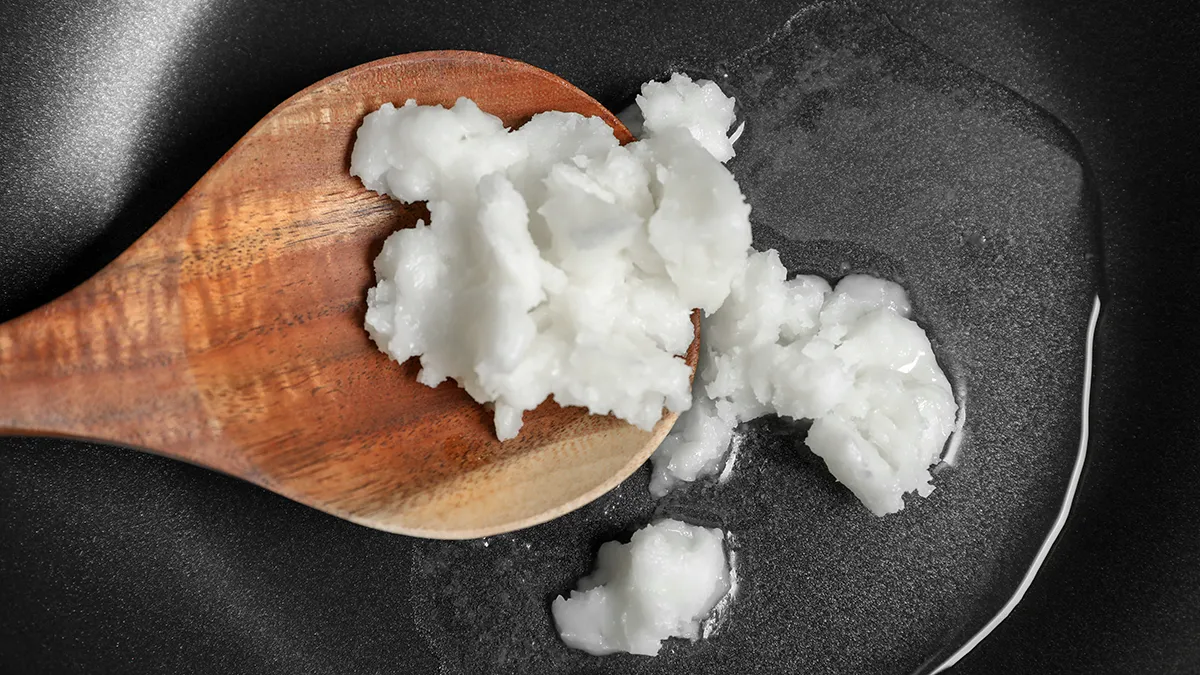 coconut oil on a spoon in an iron pan