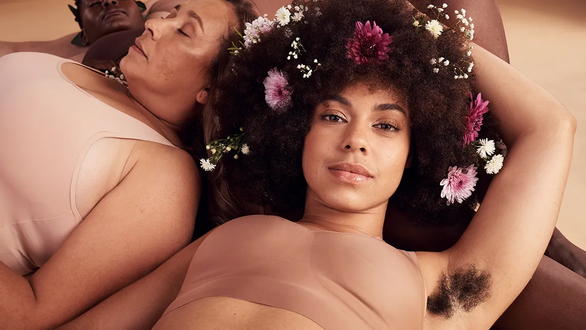 An African-American woman with flowers in her afro, laying on her back and showing a hairy armpit