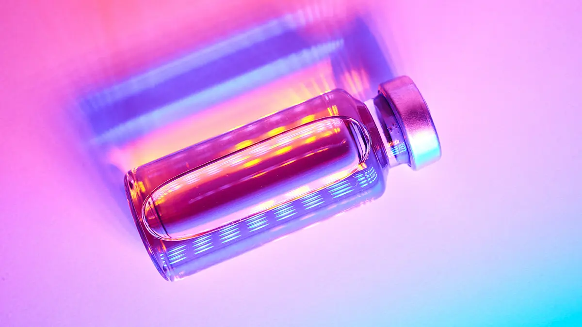 A glass vial of GLP-1 under neon lighting