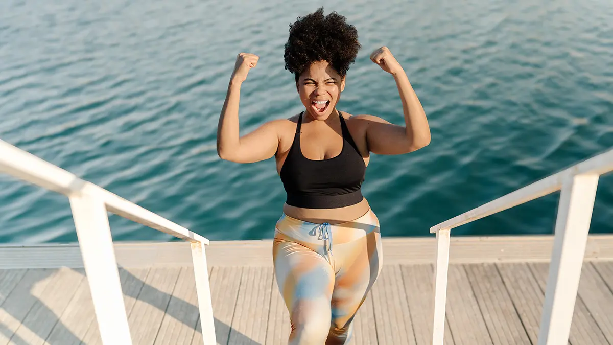 A curvy woman celebrating her weight loss success by the sea