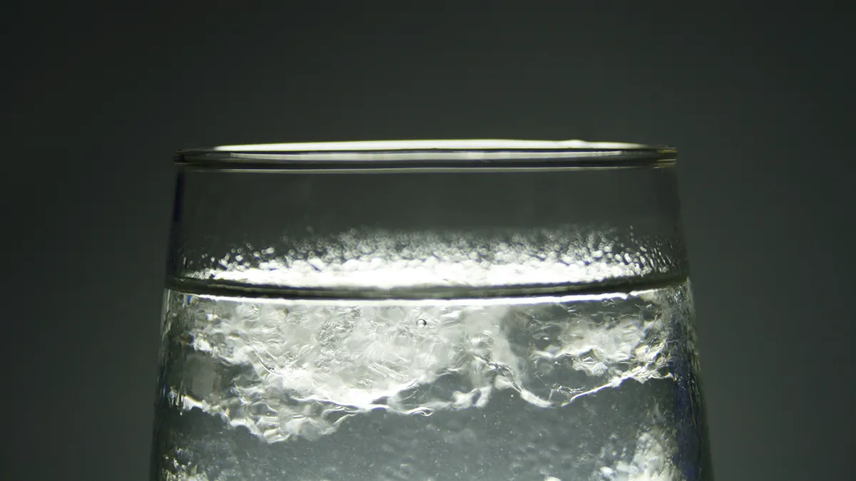 A glass of ice water on a dark background