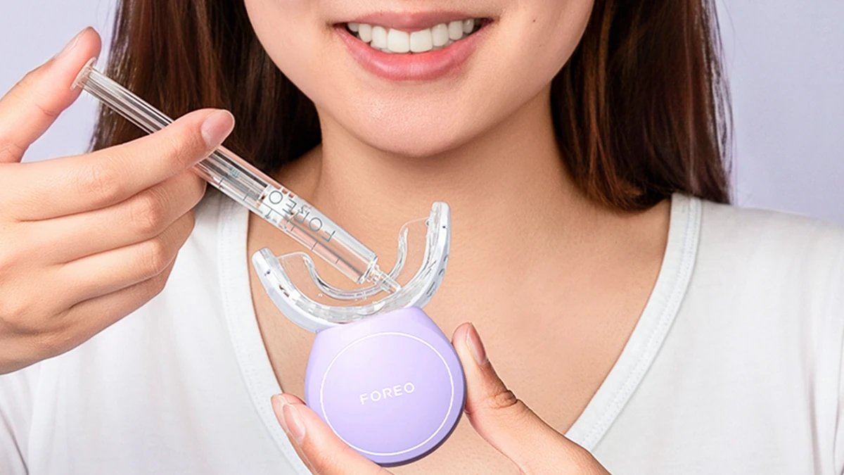 A woman applying issa advanced teeth whitening gel to the issa teeth whitening device