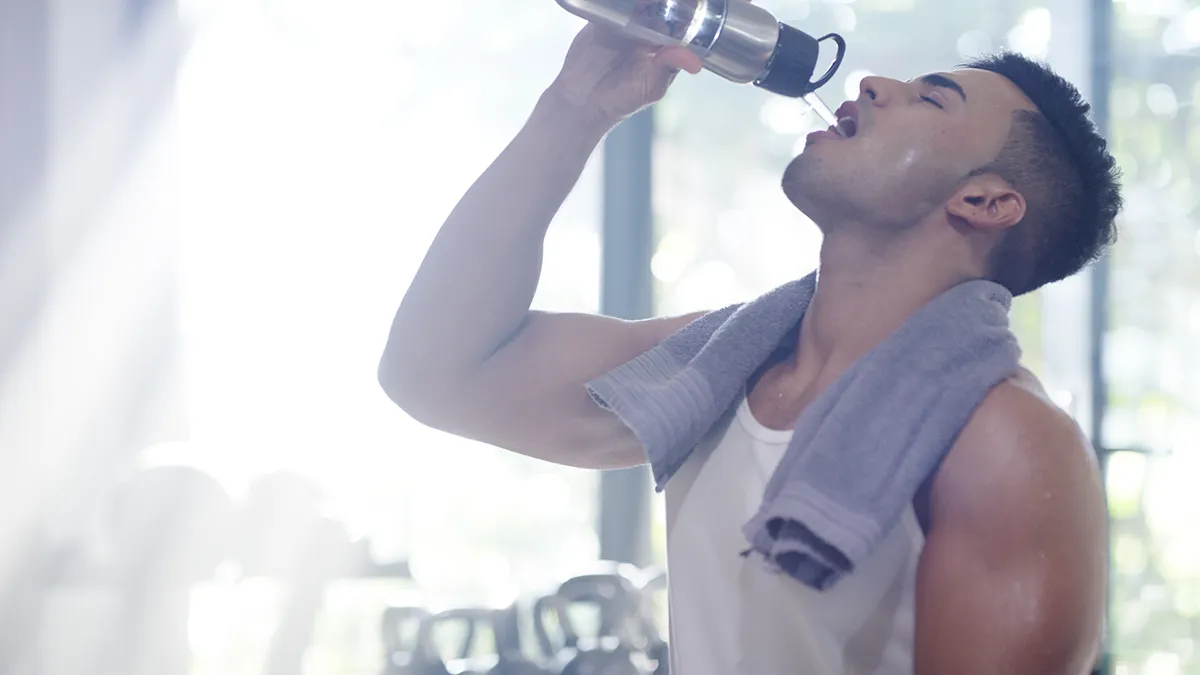 Muscular man in the gym drinking water