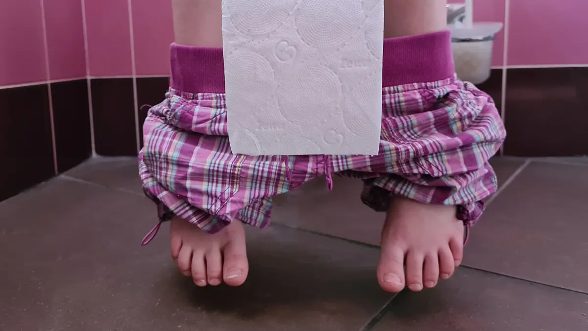 feet and pink pajama bottoms of a person sitting on the toilette