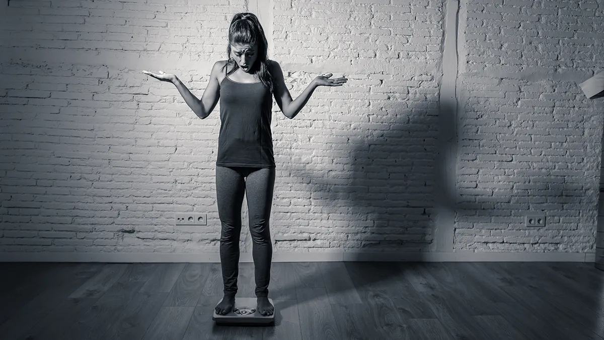 A woman weighing herself on a scale 