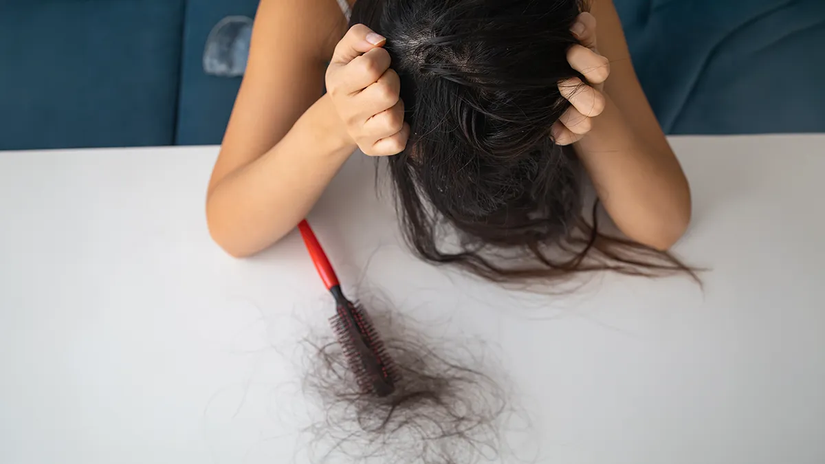 A woman distressed with the amount of hair on her hair brush