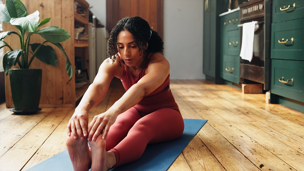A woman streatching at home on a yoga mat 