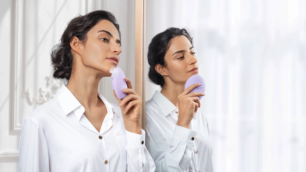 A woman using LUNA 4 facial cleansing brush