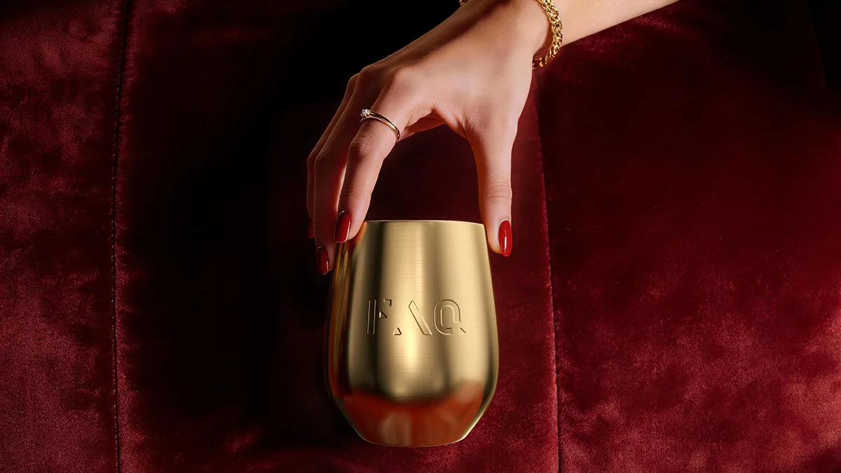 A woman with red nails gholding the golden cup full of FAQ pure women's supplement 