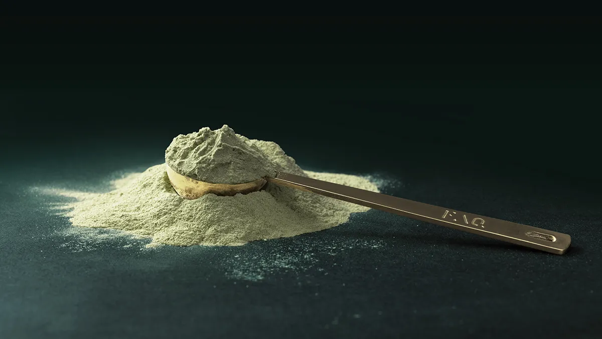 FAQ pure green powder best supplements for hormonal balance in a gold scooper on a dark background