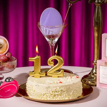 FOREO devices and cosmetics around a birthday cake with the candles showing the number 12