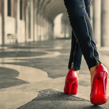 A modern woman in red high heals walking away from us symbolising The Wizard of Oz Dorothy and her red shoes 
