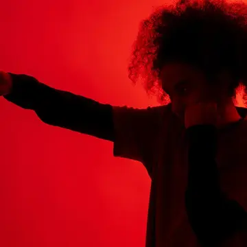 A shadow of a man with afro hair throwing a punch under red light