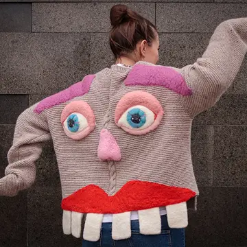 A woman dancing in a knitted jacket with face and teeth