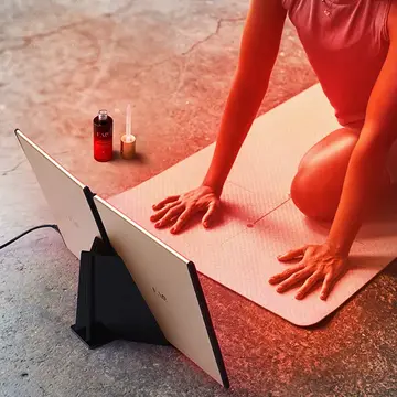 Woman doing yoga in fron of FAQ DUAL LED PANEL red light therapy at home device