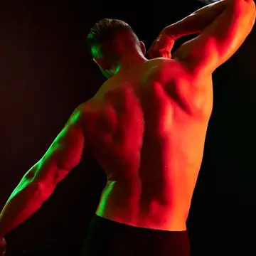 A muscular man's back in red light