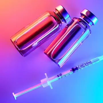 GLP-1 bottles and a syringe under neon lights