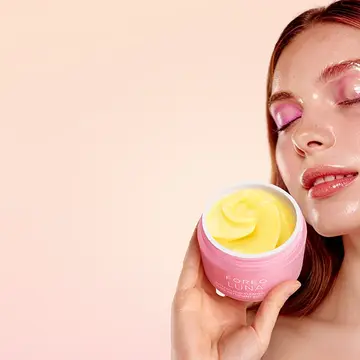A woman using LUNA Buttercloud Cleansing Balm