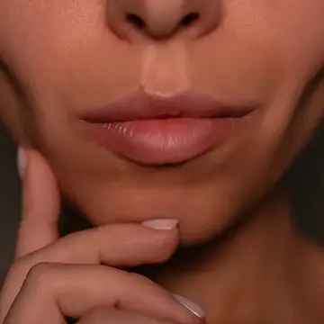 A woman with sunken cheeks wandering how to avoid Ozempic face on a dark background