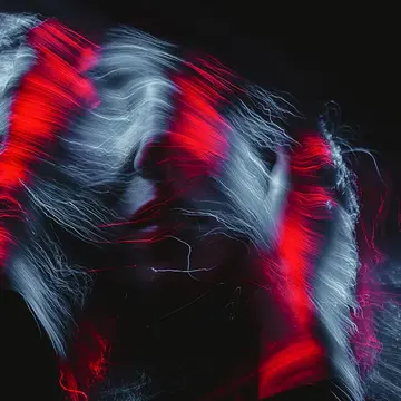 An abstract photo of a woman in the dark with red light over her hair