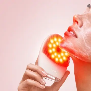 A woman using LUNA 5 LED face cleansing brush