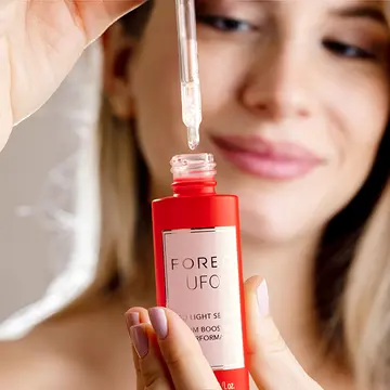 A woman using UFO LED serum for red light therapy