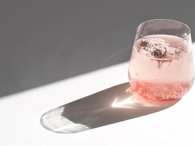 A glass filled with water and pink powder on a white surface