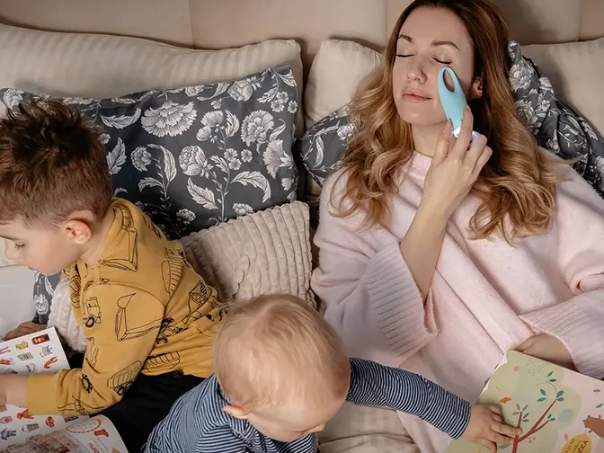 Mother's day a mom enjoying time with young children playing on the bed as she does skincare
